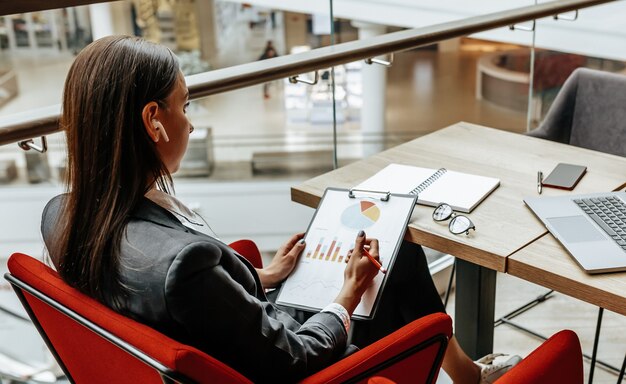 Femme d'affaires vérifie les graphiques au bureau