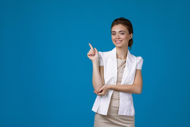 Femme d'affaires en veste blanche pointant vers le haut