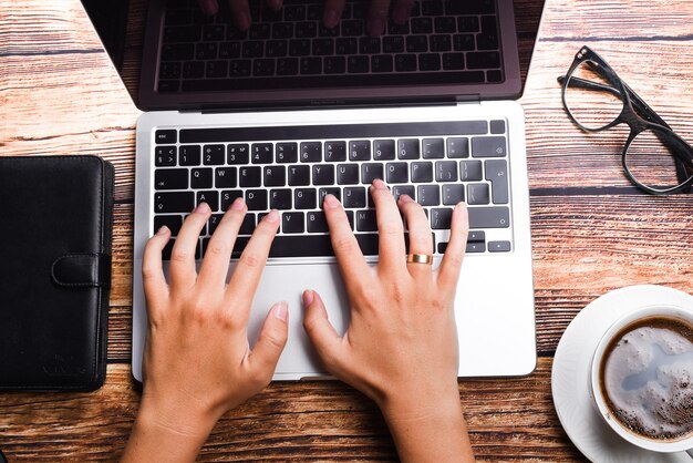 Femme d'affaires vue de dessus tapant sur ordinateur portable au lieu de travail. Femme travaillant au clavier de main de bureau à domicile. Concept de lieu de travail