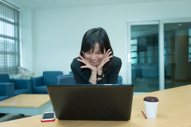 Femme d'affaires wow à partir d'un ordinateur portableRegardant le marché boursier Concept de femme thaïlandaise heureuseSecrétaire travaillant au bureau