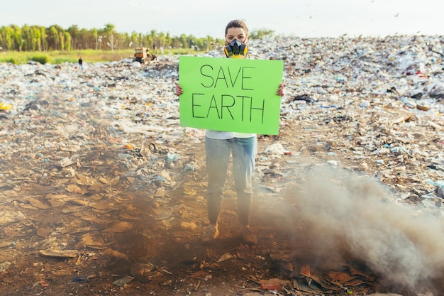 Photo une femme avec une affiche sauve la planète, un environnement contaminé par des ordures, un feu brûlant et une fumée noire