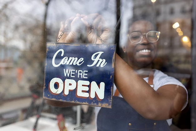 Photo une femme africaine accroche un panneau ouvert sur la porte en verre d'une épicerie à déchets zéro