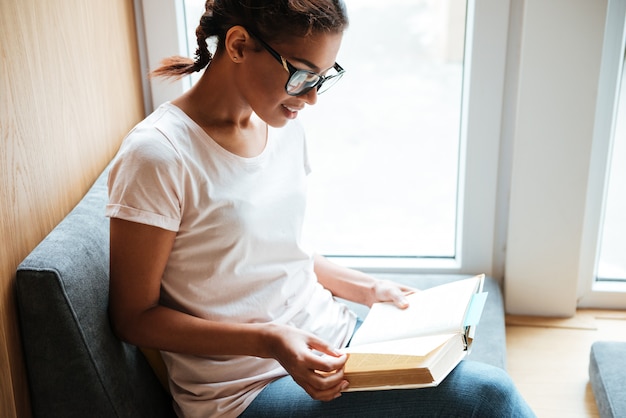 Femme africaine assise dans la bibliothèque et lire des livres.