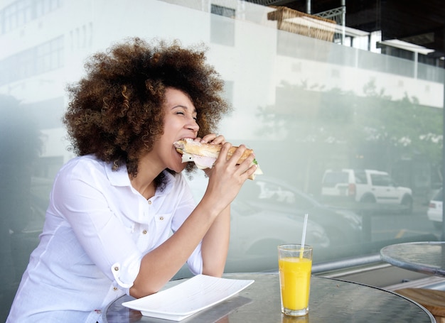 Femme africaine au café, manger un sandwich