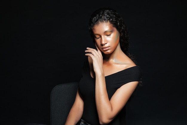 Femme africaine sur chaise en studio.