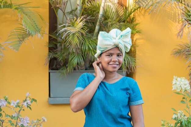 Femme africaine avec un chiffon enroulé autour de sa tête en regardant la caméra.