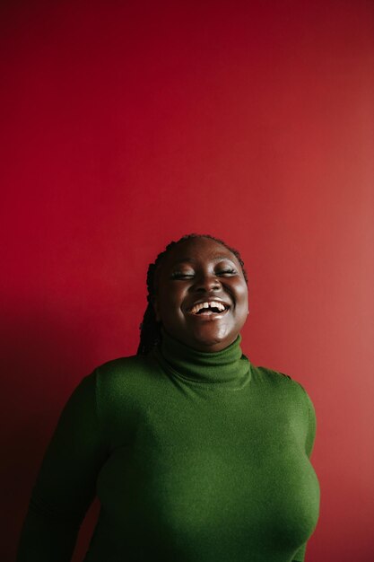 Une femme africaine confiante avec des cheveux tressés et des clips colorés gardant les yeux fermés et souriante