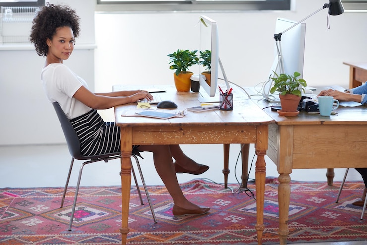 Photo femme africaine confiante ou portrait dans un bureau moderne sur ordinateur pour le développement de projets ou une entreprise en démarrage concepteur web coworking ou personne fière avec la technologie dans une agence créative ou une entreprise