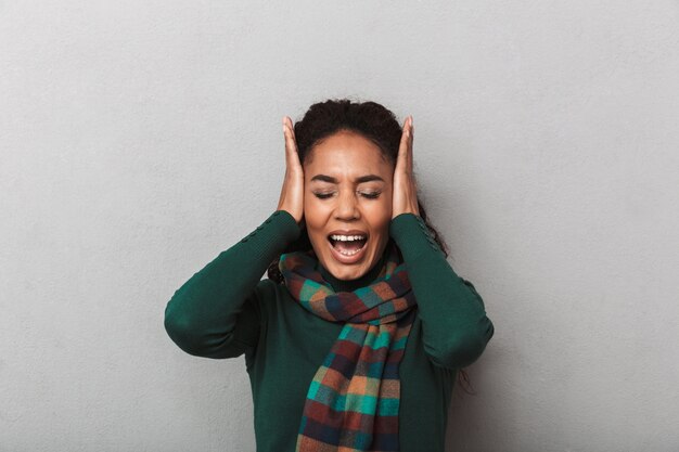 Femme africaine désespérée portant chandail debout, souffrant d'une forte migraine