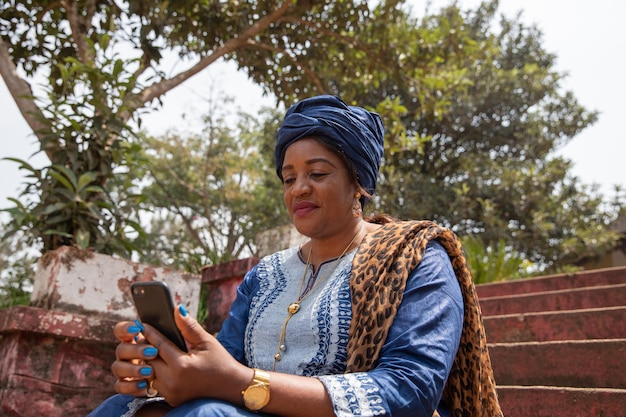 Une femme africaine habillée traditionnellement utilise son concept de femme et de technologie de smartphone