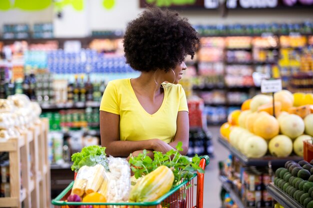 Femme africaine heureuse positive saine tenant un panier plein de fruits et légumes.