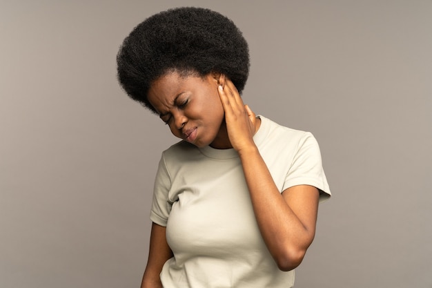 Photo une femme africaine malheureuse souffre de douleurs dans le massage du cou, blessant les muscles pour soulager la pression après le travail