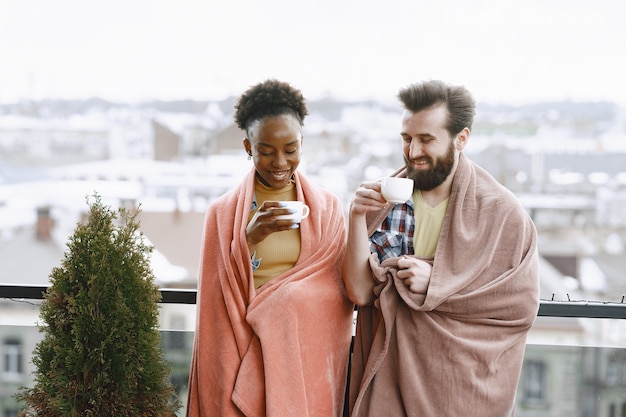 Femme africaine avec mari. Guy et fille dans un plaid. Amoureux de boire du café sur le balcon.