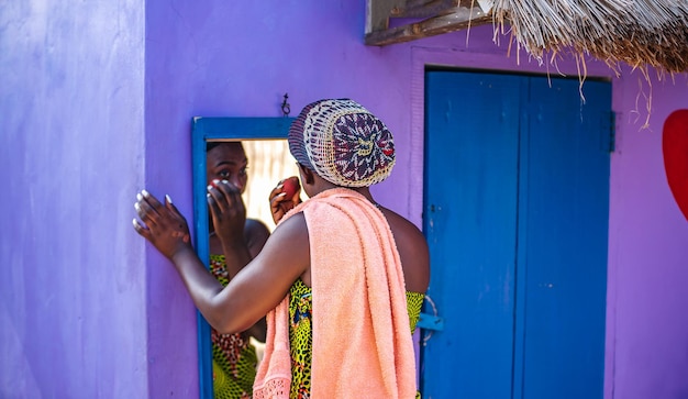 Photo une femme africaine se maquille à l'extérieur devant un miroir dans la partie tropicale du ghana