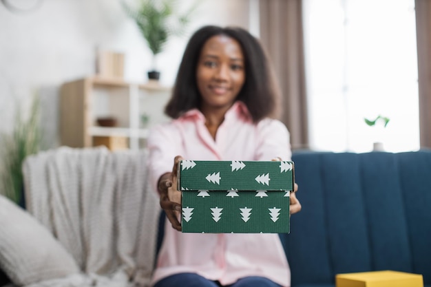 Femme africaine souriante montrant sur la boîte-cadeau de l'appareil photo