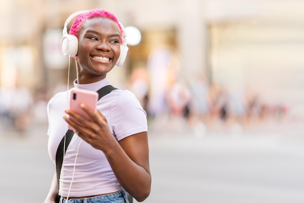 Femme africaine souriante souriant tout en écoutant de la musique à l'extérieur