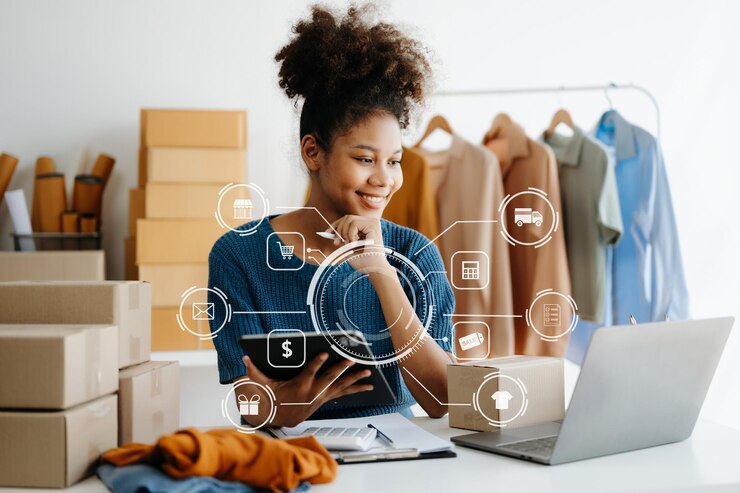 Femme africaine utilisant un ordinateur portable, un smartphone et une tablette et écrivant dans un bloc-notes au bureau moderne de son entreprise.