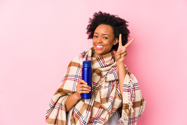 Femme afro-américaine d'âge moyen dans un camping isolé montrant le signe de la victoire et souriant largement.