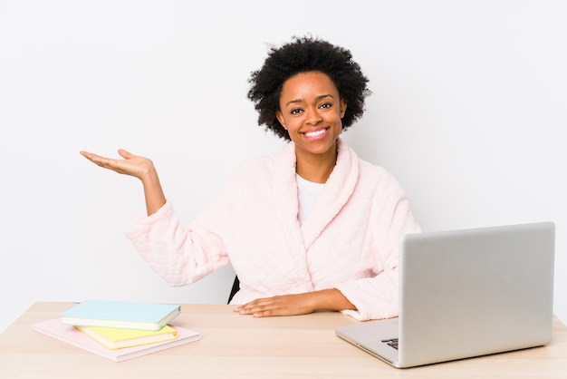 Femme Afro-américaine D'âge Moyen Travaillant à La Maison Isolé Montrant Un Espace De Copie Sur Une Paume Et Tenant Une Autre Main Sur La Taille.