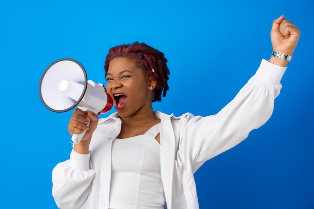 Femme afro-américaine à l'aide d'un mégaphone sur fond bleu