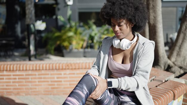 Femme afro-américaine assise sur un banc pour blessure au genou au parc