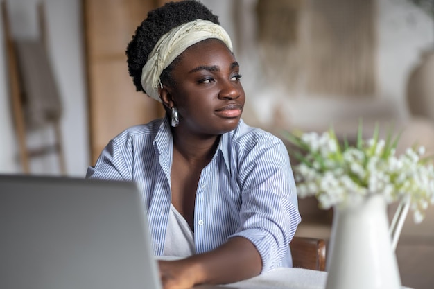 Femme afro-américaine assise à la table et travaillant sur un ordinateur portable