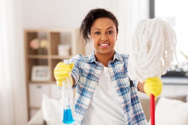 femme afro-américaine avec un balai nettoyant à la maison