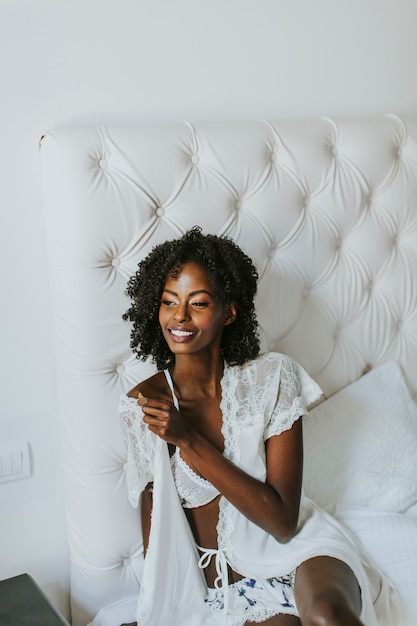 Photo femme afro-américaine en blanc posant sur le lit