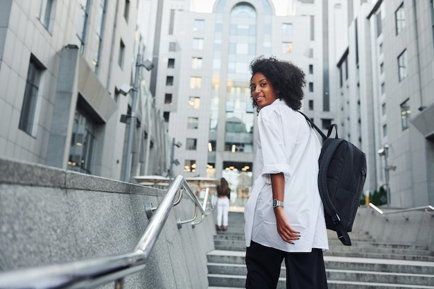 Une femme afro-américaine en bons vêtements est à l'extérieur de la ville pendant la journée