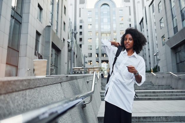 Une femme afro-américaine en bons vêtements est à l'extérieur de la ville pendant la journée