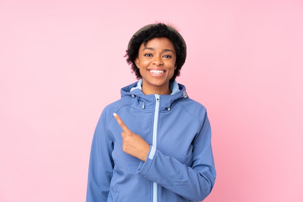 Femme afro-américaine avec chapeau d'hiver sur un mur rose isolé