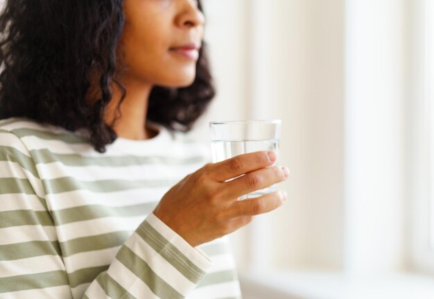 Photo femme afro-américaine coupée buvant un verre d'eau rafraîchissant le début de la journée