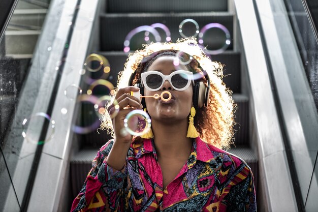 Femme afro-américaine dans le casque soufflant des bulles sur l'escalier en mouvement