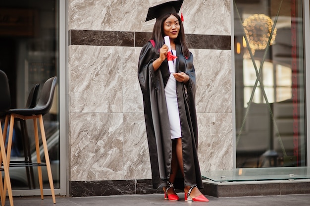 Femme afro-américaine dans une robe noire à l'obtention du diplôme