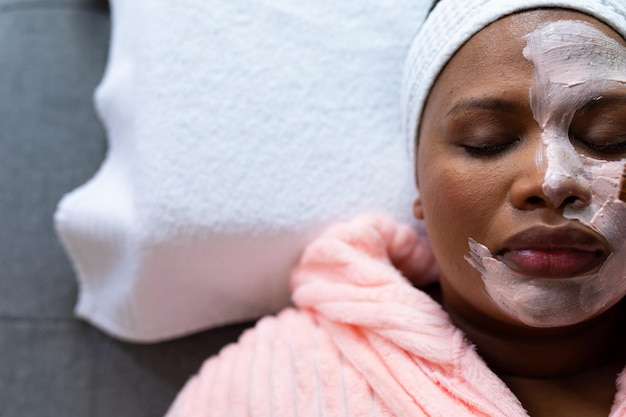 Photo une femme afro-américaine détendue avec la moitié d'un masque de beauté sur le visage au spa.