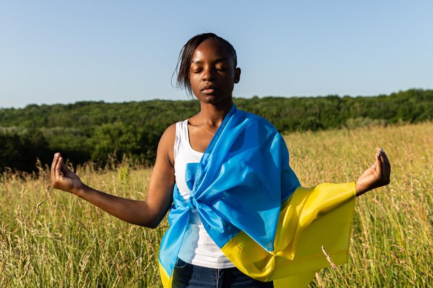 Femme afro-américaine enveloppée dans le drapeau bleu jaune ukrainien symbole national de l'Ukraine
