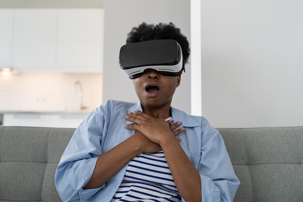 Une femme afro-américaine excitée portant un casque de technologie VR obtient un film avec un effet 3d futuriste