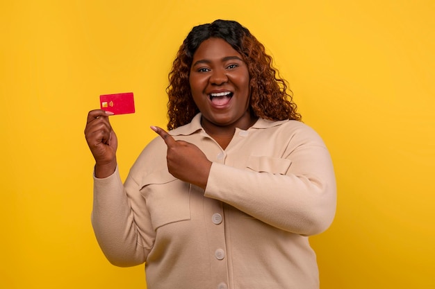 Une femme afro-américaine grosse et positive montrant sa carte de crédit.