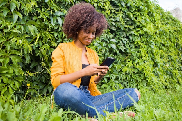 La femme afro-américaine heureuse dans la rue, parler au téléphone