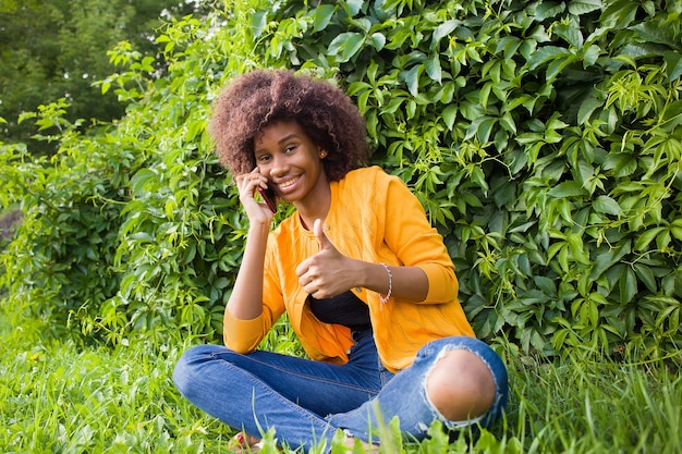 La femme afro-américaine heureuse dans la rue, parler au téléphone