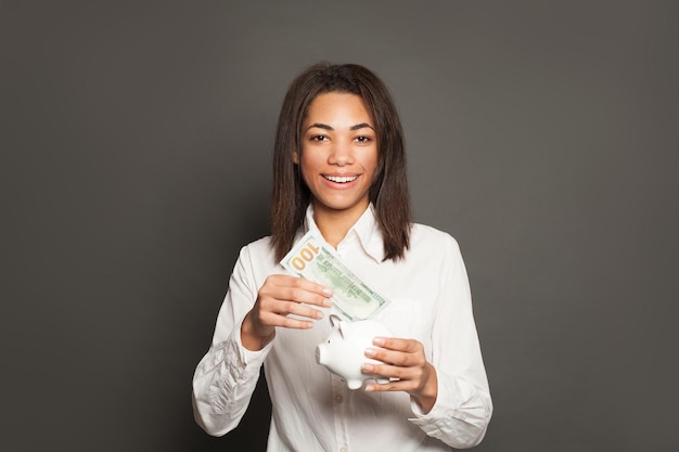 Une femme afro-américaine intelligente et prospère met un billet de 100 dollars dans sa poche.