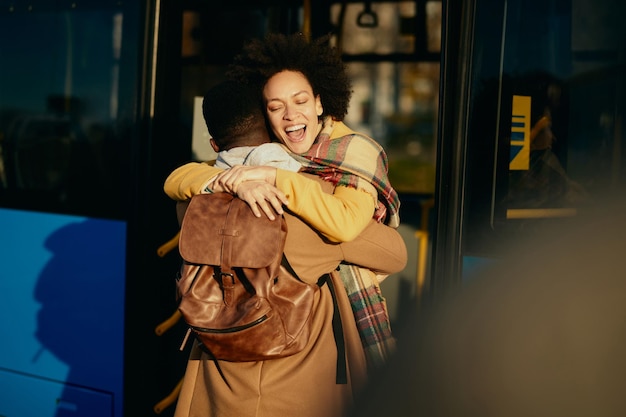 Une femme afro-américaine joyeuse embrassant son petit ami en sortant d'un bus