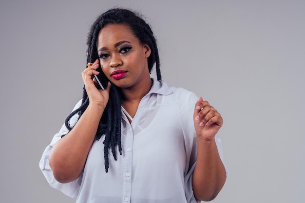 Femme afro-américaine avec de longues nattes noires dreadlocks en studio sur fond blanc