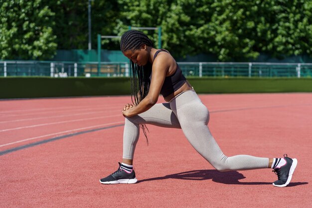 Une femme afro-américaine avec de longues tresses bénéficie d'un exercice efficace pour les muscles des fesses sur le stade de la ville.