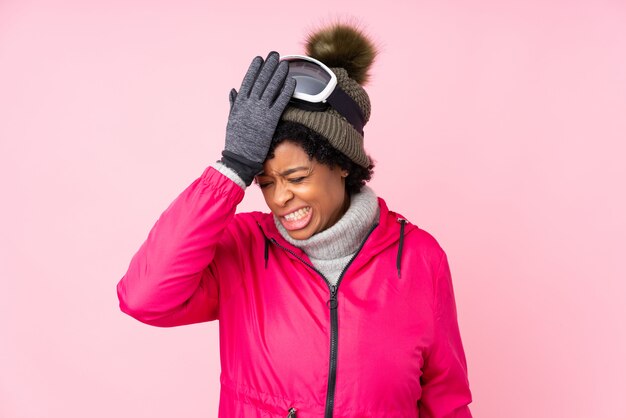 Femme afro-américaine avec des lunettes de neige sur mur rose