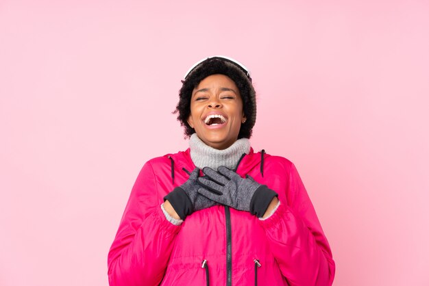 Femme afro-américaine avec des lunettes de ski sur mur rose isolé