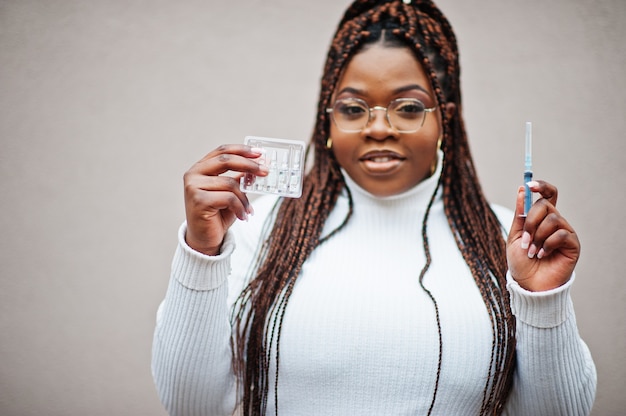 Femme afro-américaine à lunettes tenir le vaccin seringue.