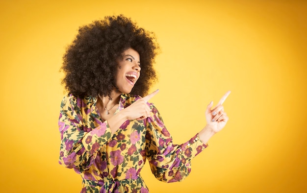 Une femme afro-américaine mixte, souriante et amicale montre le coin supérieur droit