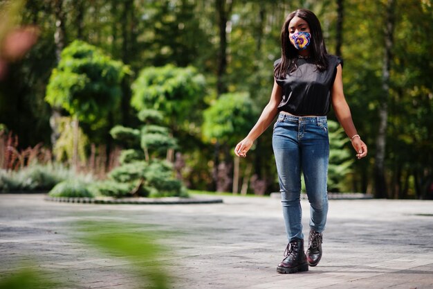 Une femme afro-américaine à la mode porte un masque facial fait à la main posant en plein air Nouvelle vie normale