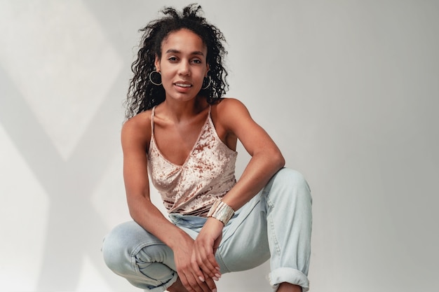 femme afro-américaine noire en tenue élégante jeans et haut sur blanc